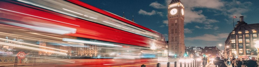 Red London bus driving past Big Ben